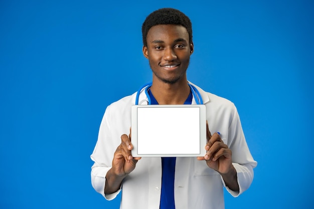Porträt eines afroamerikanischen männlichen Arztes mit weißem Kittel mit digitalem Tablet im Studio