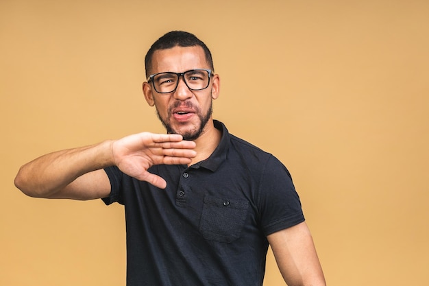 Porträt eines afroamerikanischen schwarzen Mannes, der die Hand in einem Stoppschild hält und Sie daran hindert, etwas Schlechtes mit besorgtem Gesichtsausdruck isoliert über beigem Hintergrund in die Kamera zu blicken