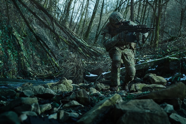 Porträt eines Airsoft-Spielers in professioneller Ausrüstung im Helm, der auf ein Opfer mit einer Waffe im Wald abzielt. Soldat mit Waffen im Krieg