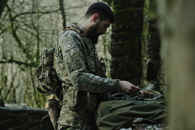 Porträt eines Airsoft-Spielers in professioneller Ausrüstung mit Maschinengewehr im Wald. Soldat mit Waffen im Krieg