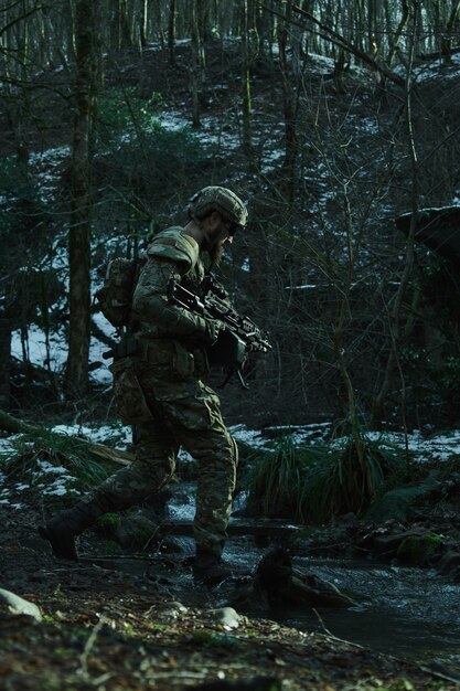 Porträt eines Airsoft-Spielers in professioneller Ausrüstung mit Maschinengewehr im Wald. Soldat mit Waffen im Krieg