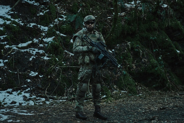 Porträt eines Airsoft-Spielers in professioneller Ausrüstung mit Maschinengewehr im Wald. Soldat mit Waffen im Krieg