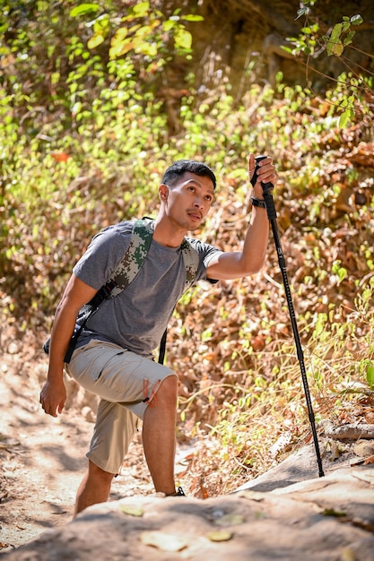 Porträt eines aktiven, fitten und müden asiatischen Reisenden mit Trekkingausrüstung, der den Wald erkundet