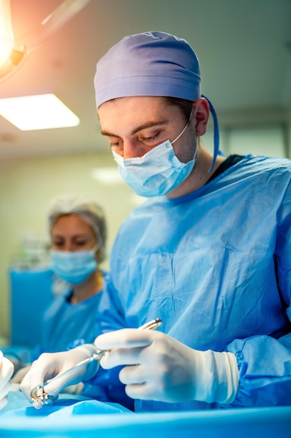 Porträt eines Arztes oder Facharztes Vertikales Porträt Mann in Scrubs Heller Hintergrund mit OP-Saal Nahaufnahme