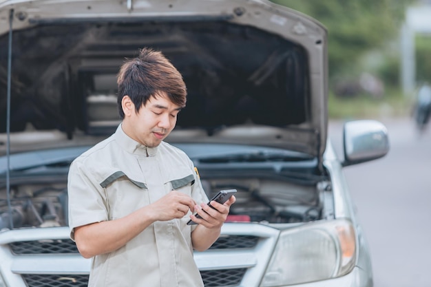 Porträt eines asiatischen automechanikers, der eine liste des autoinnenraums für einen werkstattkunden überprüft.