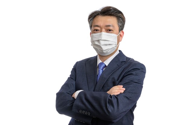 Porträt eines asiatischen Geschäftsmannes mittleren Alters, der eine weiße Gesichtsmaske trägt.