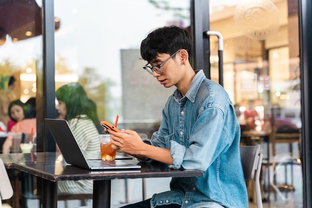 Porträt eines asiatischen männlichen Studenten, der in einem Café sitzt