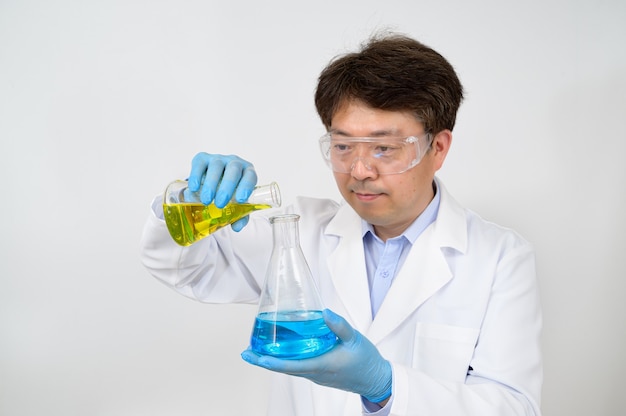 Porträt eines asiatischen männlichen Wissenschaftlers im mittleren Jahr, der ein weißes Laborkleid und Handschuhe trägt und einen experimentellen Behälter in der Hand hält.