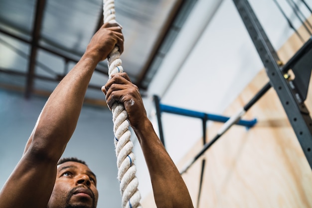 Porträt eines athletischen Mannes, der Kletterübung an der Turnhalle tut. Crossfit, Sport und gesundes Lifestyle-Konzept.