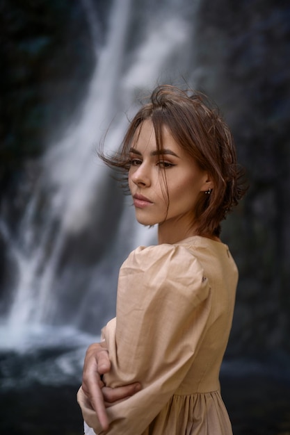 Porträt eines attraktiven brünetten Mädchens vor dem Hintergrund eines Wasserfalls