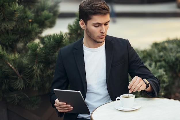 Porträt eines attraktiven und seriösen kaukasischen Mannes in lässigem Anzug, der Nachrichten in sozialen Netzwerken mit morgendlicher Kaffeepause eingibt Technologie-Geschäftsleute und Lifestyle-Konzept