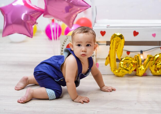 Porträt eines Babys in einer Kusskabine, die mit Herzen und Luftballons geschmückt ist