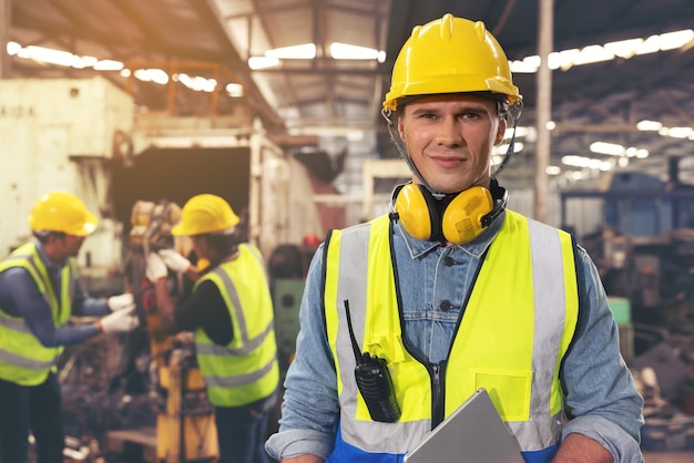 Porträt eines bärtigen Fabrikarbeiters in einem Hardhat, der auf das Foto starrt, während er in einer Werkstatt, einem Kopierraum und einer industriellen Fabriktechnik steht.