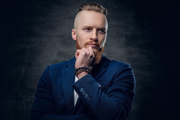 Porträt eines bärtigen, rothaarigen hipster-männchens, gekleidet in eine blaue jacke auf grauem hintergrund.