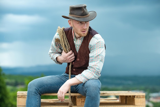 Porträt eines Bauern- oder Cowboy-Cowboys im Freien mit Lasso-Seil auf Himmelshintergrund