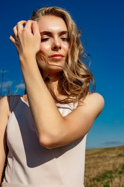 Porträt eines blonden Modells des jungen Mädchens, das an einem sonnigen Tag steht und aufwirft