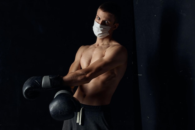 Porträt eines Boxers mit medizinischer Maske und schwarzen Handschuhen auf isoliertem Hintergrund