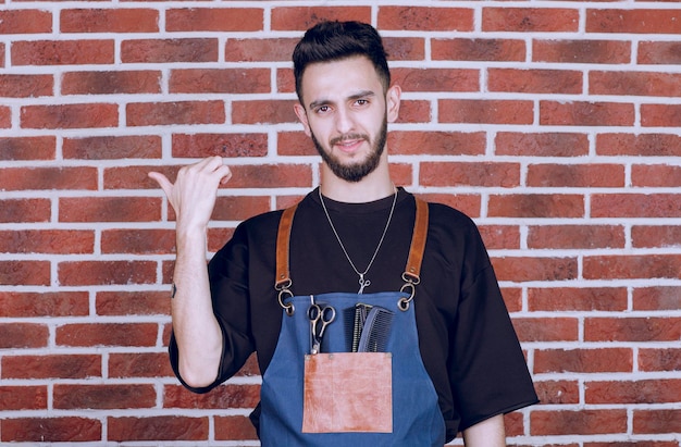 Porträt eines brünetten Friseurs, der an der Wand steht. Foto in hoher Qualität