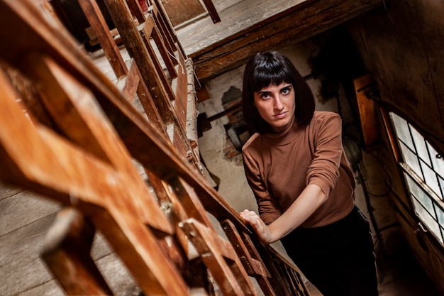 Porträt eines brünetten Mädchens in einer Treppe eines verlassenen Hauses, Bild bei schwachem Licht