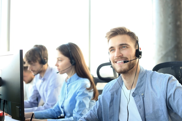 Porträt eines call-center-mitarbeiters in begleitung seines teams. lächelnder kundendienstmitarbeiter bei der arbeit.