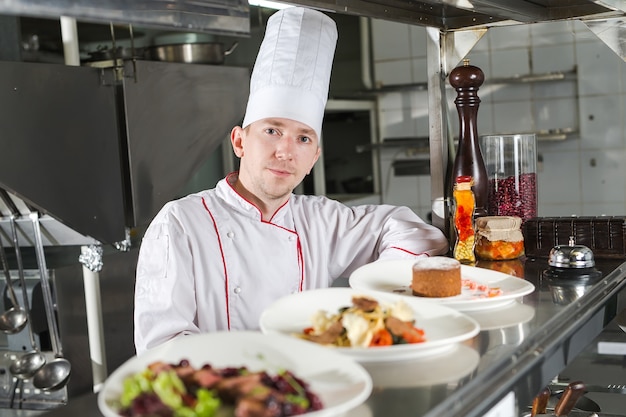 Porträt eines Chefs mit gekochtem Essen in der Küche im Restaurant.