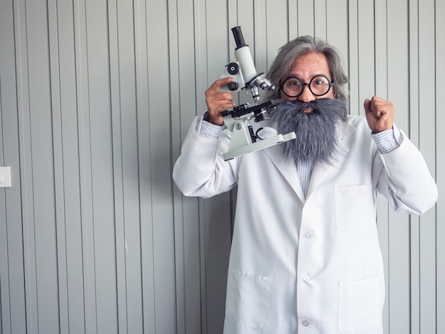 Foto porträt eines doktors vor einem grauen schmutzhintergrund mit mikroskop