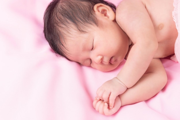 Porträt eines einen Monat alten schlafenden, neugeborenen Mädchens auf einer rosa Decke. Konzept Portraitstudio Mode Neugeborenes.