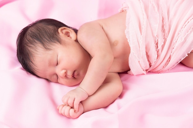 Porträt eines einen Monat alten schlafenden, neugeborenen Mädchens auf einer rosa Decke. Konzept Portraitstudio Mode Neugeborenes.