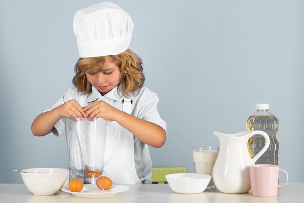 Porträt eines einjährigen Kindes mit Kochmütze und Schürze, das Obstsalat macht und Essen in der Küche kocht c