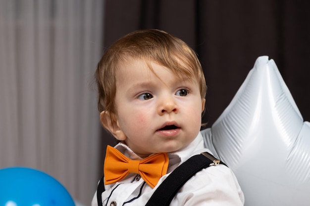 Foto porträt eines einjährigen rothaarigen jungen, der ein hemd mit fliege und hosenträgern trägt