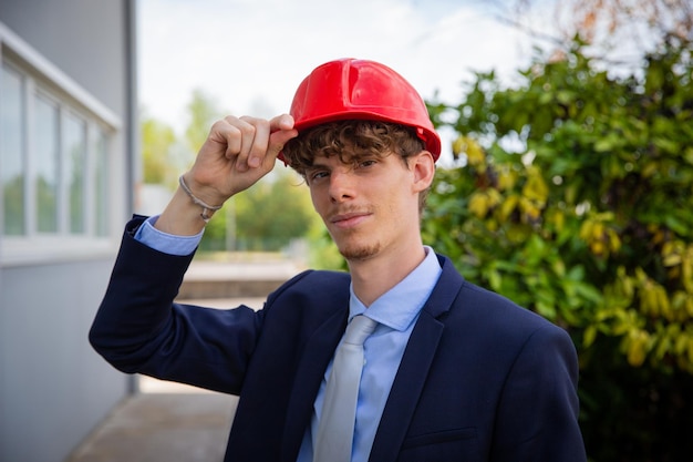 Porträt eines elegant gekleideten erfolgreichen Ingenieurs, der einen Schutzhelm mit der Hand hält