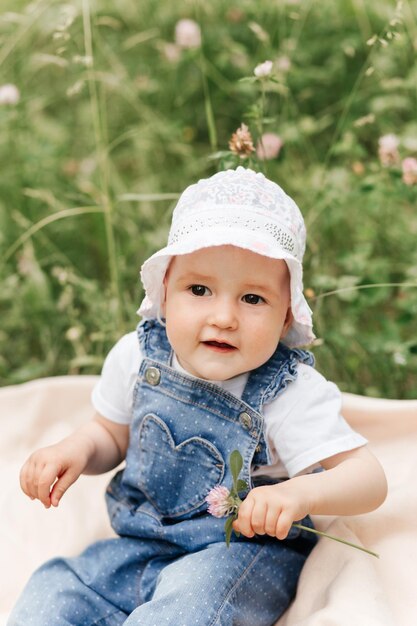 Foto porträt eines entzückenden, charmanten kleinkindmädchens auf einer blumenwiese lächelndes, glückliches babykind am sommertag mit bunten blumen im freien glück und sommerzeit