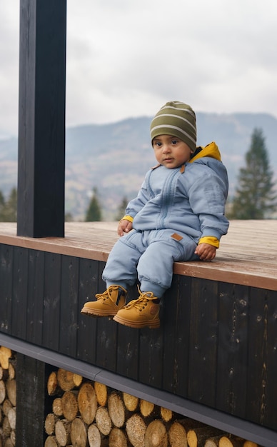 Foto porträt eines entzückenden kleinen jungen, der einen blauen overall und sicherheitsstiefel trägt