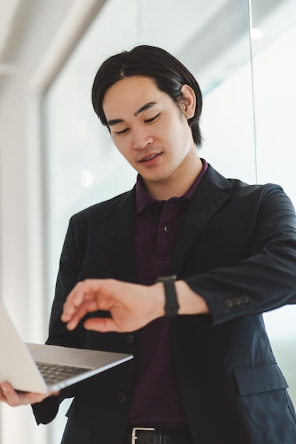 Porträt eines erfolgreichen asiatischen Geschäftsmanns, der einen Laptop benutzt und an einem Online-Planungsprojekt arbeitet