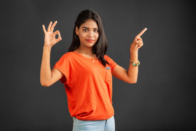 Porträt eines erfolgreichen fröhlichen jungen Mädchens, das etwas mit der Hand oder dem Finger mit einem glücklich lächelnden Gesicht zeigt und präsentiert