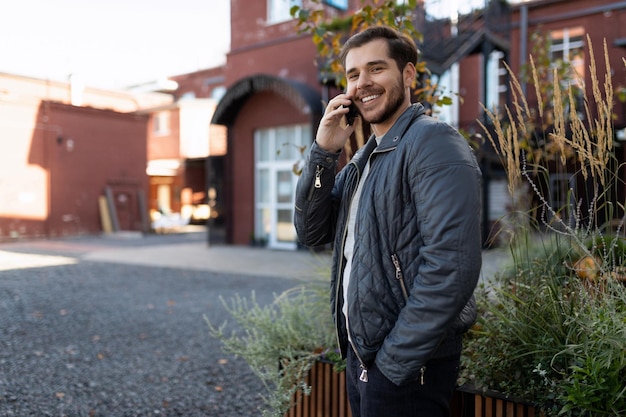 Porträt eines erfolgreichen männlichen Unternehmers, der außerhalb des Büros mit einem Mobiltelefon telefoniert