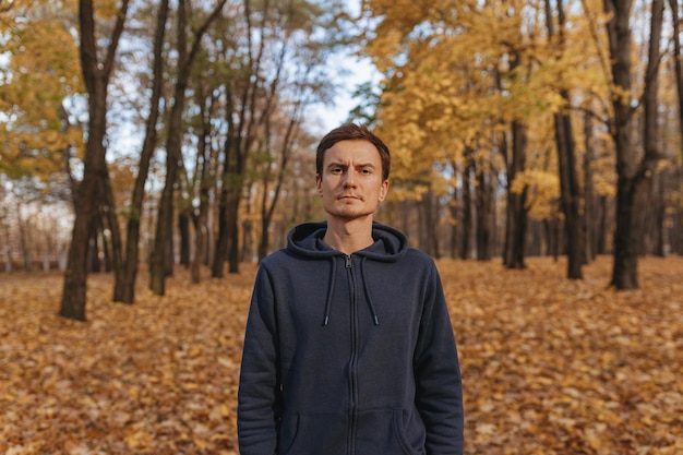 Porträt eines ernsthaften, selbstbewussten Sportlers in Activewear, der im Herbstpark auf dem Weg steht