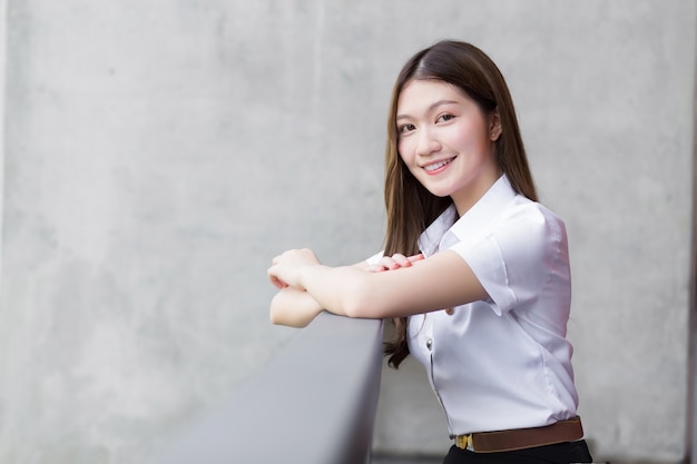 Porträt eines erwachsenen thailändischen Studenten in Universitätsstudentenuniform. Asiatisches schönes Mädchen, das glücklich an der Universität lächelt