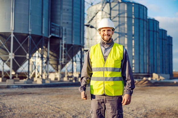 Porträt eines Fabrikarbeiters, der vor Silos voller Getreide oder Mais steht