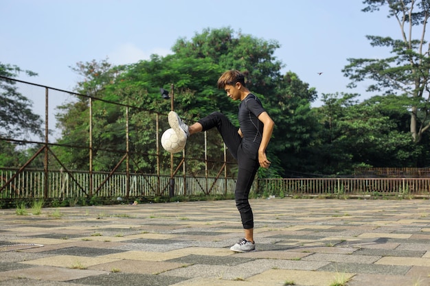 Porträt eines fitten jungen Mannes, der im Freien mit einem Fußball jongliert
