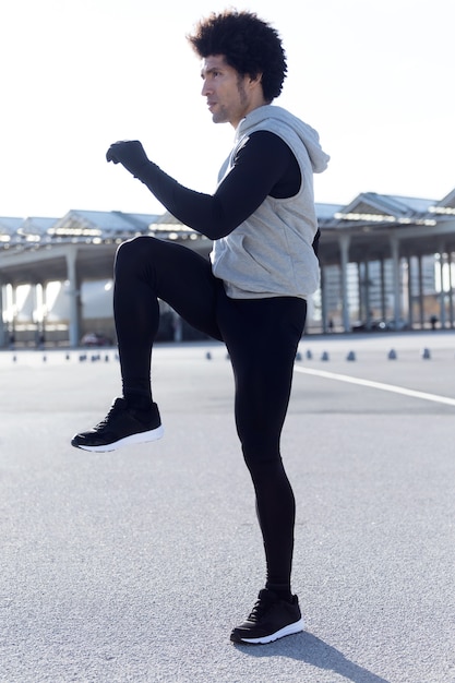 Porträt eines fitten und sportlichen jungen Mannes, der sich in der Stadt ausdehnt.