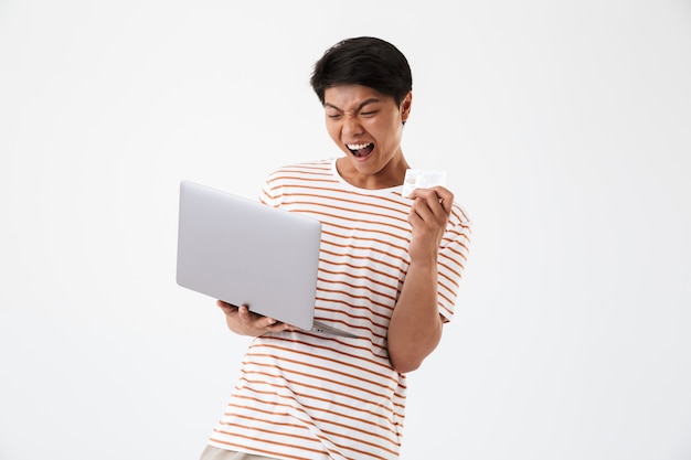 Porträt eines freudigen jungen asiatischen Mannes, der Laptop hält