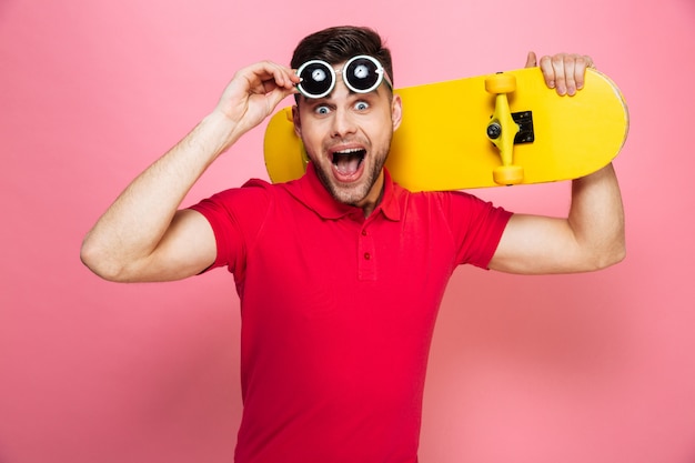 Porträt eines freudigen jungen Mannes in der Sonnenbrille, die aufwirft