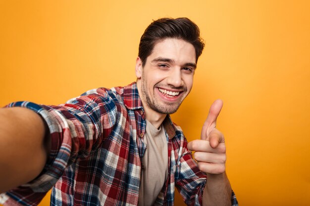 Porträt eines fröhlichen jungen Mannes, der ein Selfie macht