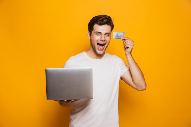 Porträt eines fröhlichen jungen Mannes, der Laptop-Computer hält