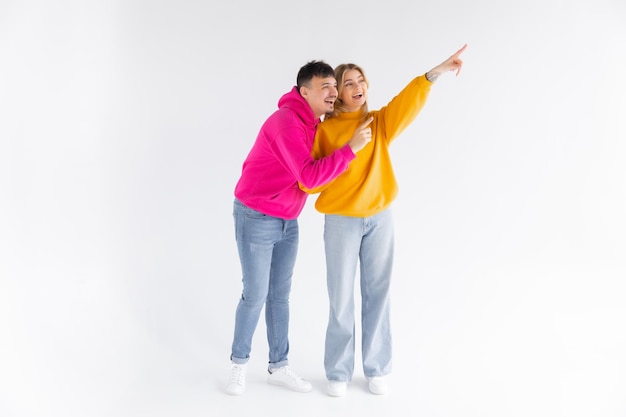 Porträt eines fröhlichen jungen Paares, das Hoodies trägt, die isoliert über weißem Hintergrund stehen, ok, gest
