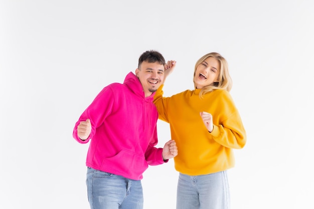 Porträt eines fröhlichen jungen Paares, das Hoodies trägt, die isoliert über weißem Hintergrund stehen, ok, gest