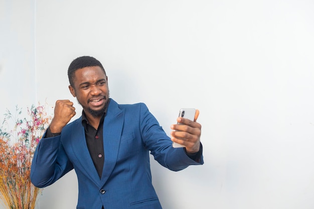 Porträt eines fröhlichen jungen schwarzen Mannes, der eine Nachricht auf einem Handy sendet. Ein glücklicher afroamerikanischer Mann, der ein Smartphone benutzt, genießt das Chat und die Online-Nachrichten in sozialen Netzwerken.
