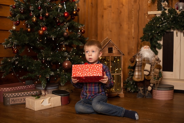 Porträt eines fröhlichen kleinen Jungen nahe Weihnachtsbaum