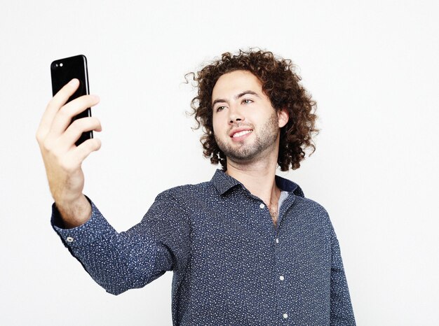 Porträt eines fröhlichen Mannes, der ein Selfie auf weißem Hintergrund macht